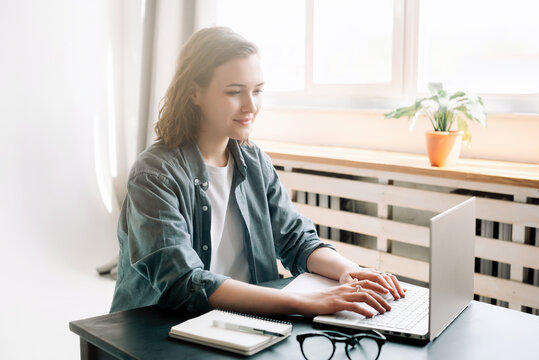 Young woman using laptop computer in a modern office setting and student girl working from the comfort of home. Online work, study, freelance, business, and office lifestyle concept.