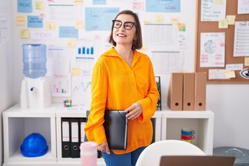 Middle age woman business worker smiling confident holding binder at office