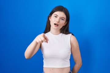 Fototapeta na wymiar Young caucasian woman standing over blue background pointing displeased and frustrated to the camera, angry and furious with you
