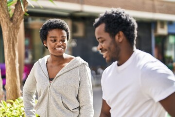 African american man and woman couple speaking together at street