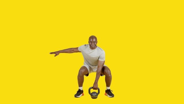 African sportive man doing alternate squats with kettlebell
