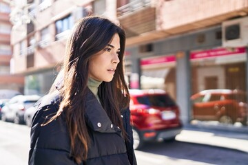 Young beautiful hispanic woman looking to the side with serious expression at street