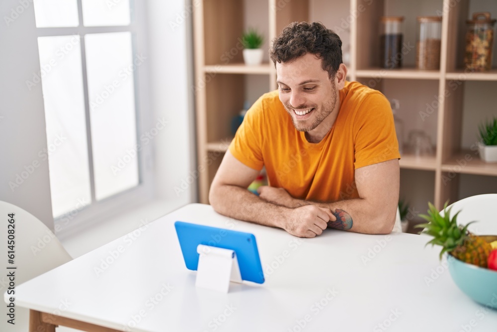 Sticker young hispanic man watching video on touchpad at home