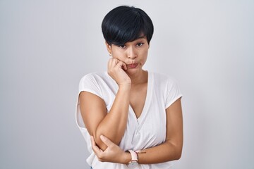 Young asian woman with short hair standing over isolated background looking stressed and nervous with hands on mouth biting nails. anxiety problem.