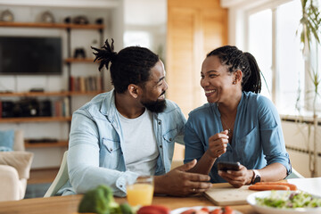 Fototapeta premium Happy African American couple having fun during breakfast time at home