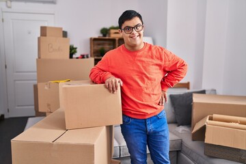 Down syndrome man smiling confident leaning on package at new home
