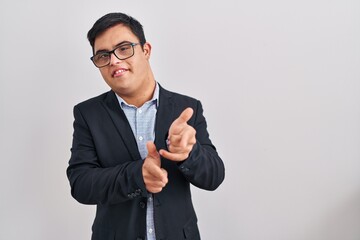 Young hispanic man with down syndrome wearing business style pointing fingers to camera with happy and funny face. good energy and vibes.