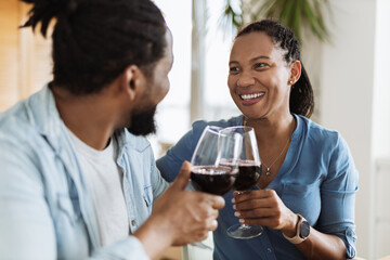 Young African-American couple talking while drinking red wine at home