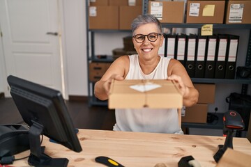 Middle age woman ecommerce business worker holding package at office