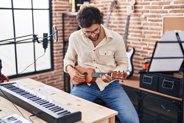 Young hispanic man musician playing ukulele at music studio