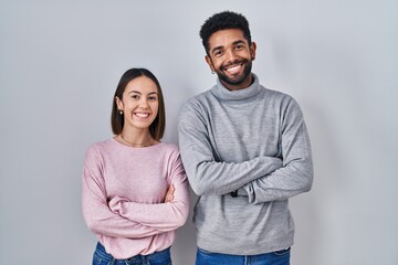 Young hispanic couple standing together happy face smiling with crossed arms looking at the camera....