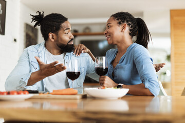Young African American couple talking while drinking red wine during a meal at home