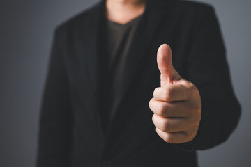 Portrait of a businessman in a suit standing thumbs up, half body and not showing face.