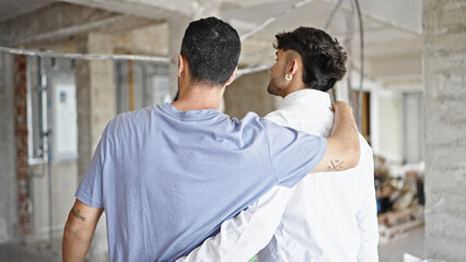 Fototapeta premium Two men couple hugging each other looking around at construction site