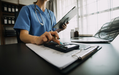 Fototapeta premium Young doctor with diary sitting at desk in medical clinic