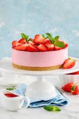 No bake strawberry cheesecake decorated with fresh berries and mint on a cake stand. Summer  dessert. Selective focus
