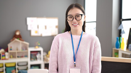Young chinese woman preschool teacher smiling confident standing at kindergarten