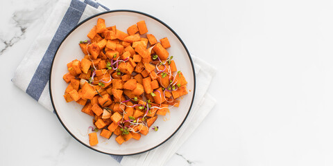 Baked sweet potato slices in a plate on the table. Healthy eating. Vegan dish. Copy space
