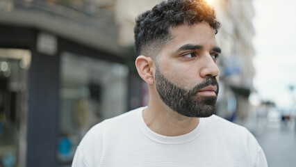 Young hispanic man looking to the side with serious expression at street