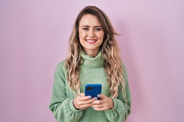 Young caucasian woman using smartphone typing message smiling with a happy and cool smile on face. showing teeth.