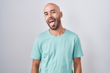 Middle age bald man standing over white background sticking tongue out happy with funny expression. emotion concept.
