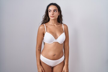Fototapeta premium Young hispanic woman wearing white lingerie smiling looking to the side and staring away thinking.