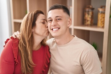 Man and woman mother and son hugging each other and kissing sitting on table at home