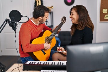 Middle age man and woman musicians having guitar class at music studio