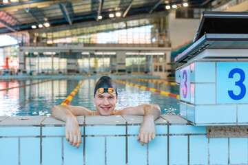 Portrait of a young professional athlete, a swimmer with a black swimming cap looking at the camera...