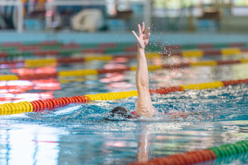 Professional female athlete swimming backstroke in the pool, arms movement. Competitive swimming...