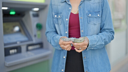 Young beautiful hispanic woman counting chilean pesos banknotes at bank teller