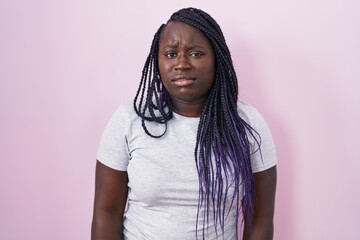 Young african woman standing over pink background looking sleepy and tired, exhausted for fatigue and hangover, lazy eyes in the morning.