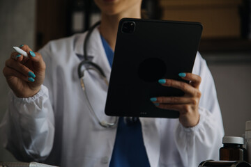 Doctor working with laptop computer and writing on paperwork. Hospital background.