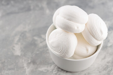 Zephyr marshmallows in bowl on a gray background. Sweet dessert marshmallows on concrete. Copy space