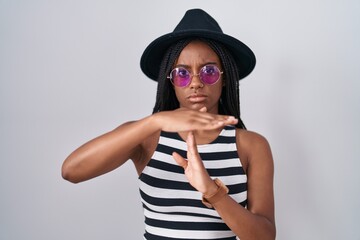 Young african american with braids wearing hat and sunglasses doing time out gesture with hands, frustrated and serious face