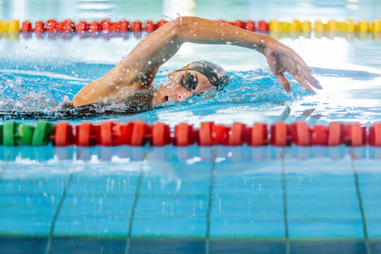 Professional female swimmer swimming the front crawl stroke. Freestyle competition concept.
