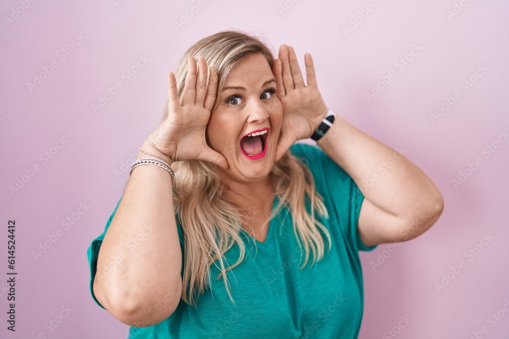 Canvas Prints Caucasian plus size woman standing over pink background smiling cheerful playing peek a boo with hands showing face. surprised and exited