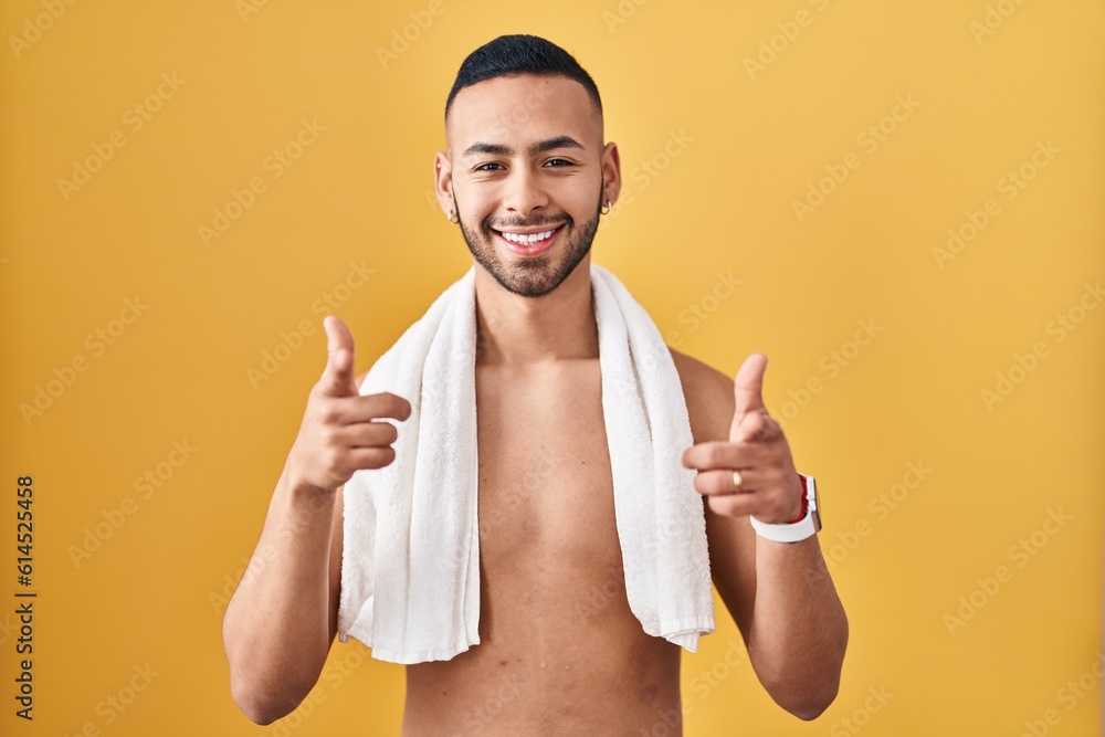 Canvas Prints Young hispanic man standing shirtless with towel pointing fingers to camera with happy and funny face. good energy and vibes.