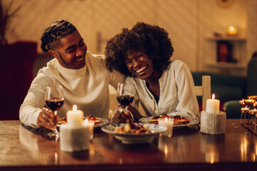 Fototapeta na wymiar African american couple having romantic date and drinking wine at home