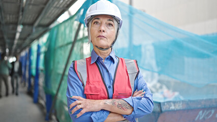 Middle age grey-haired woman builder standing with relaxed expression and arms crossed gesture at street