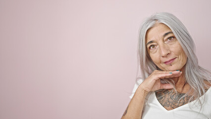 Middle age grey-haired woman smiling confident standing over isolated pink background