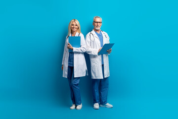 Professional medical team elderly doctors posing on blue background