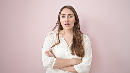 Fototapeta premium Young beautiful hispanic woman standing with serious expression and arms crossed gesture over isolated pink background