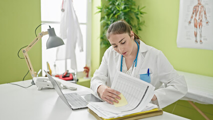 Young beautiful hispanic woman doctor looking for medical report at clinic