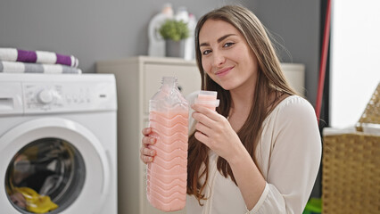 Young beautiful hispanic woman smiling confident smelling detergent at laundry room