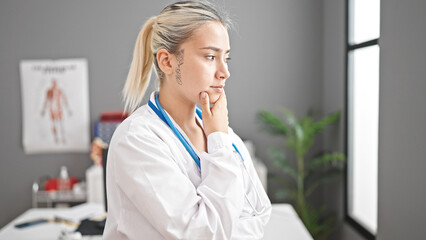 Young beautiful hispanic woman doctor standing with doubt expression thinking at clinic