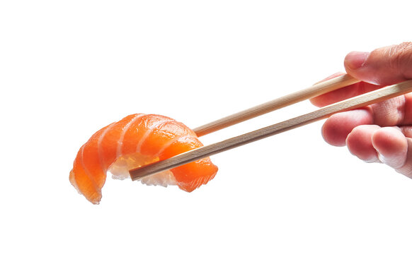  Hand of man holding salmon nigiri with chopsticks over isolated white background
