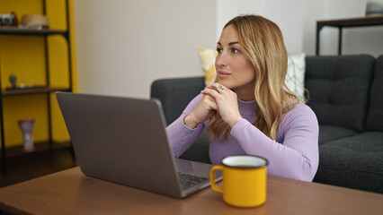 Young beautiful hispanic woman using laptop drinking coffee at home