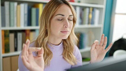 Young beautiful hispanic woman using computer doing meditation at library university