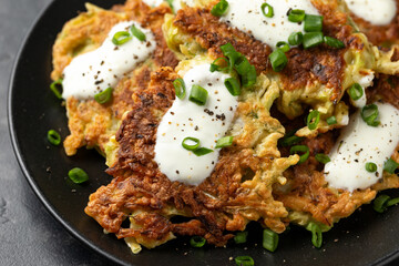Cabbage pancake with greek yogurt on black plate